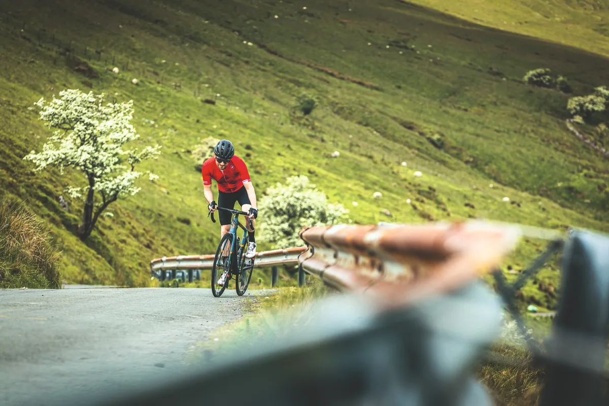 Male cyclist riding up a hill in Wales