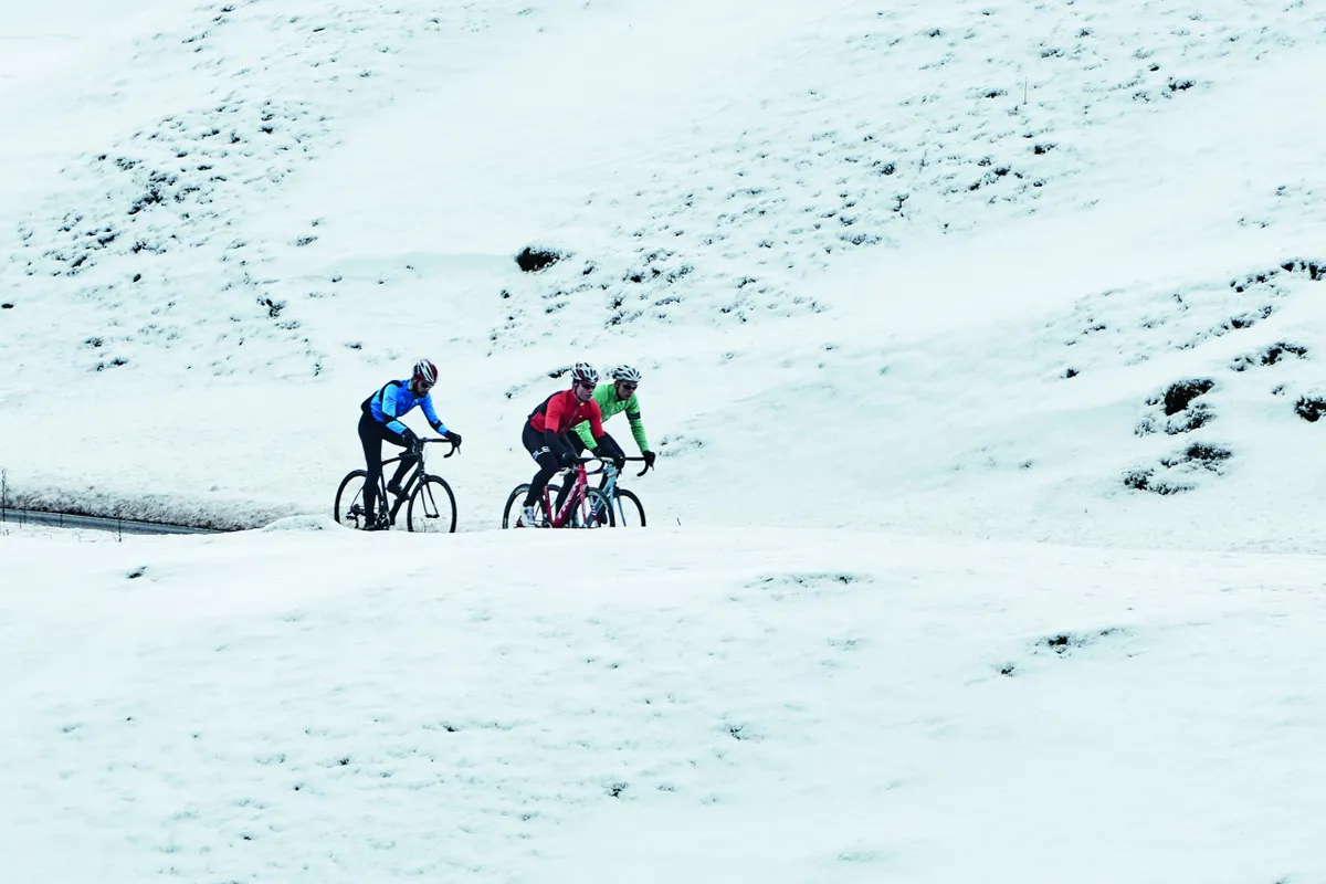 Three road riders riding through desolate snowy landscape