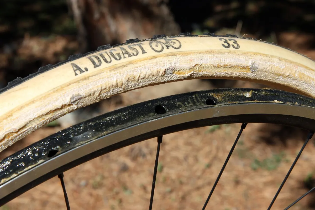 A Dugast tubular cyclocross tyre dismounted from the rim, showing a glued rim.