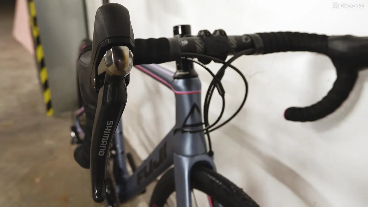 Close-up detail of the handlebars, brake levers and gear shifters on the Fuji Supreme 2.3 road bike