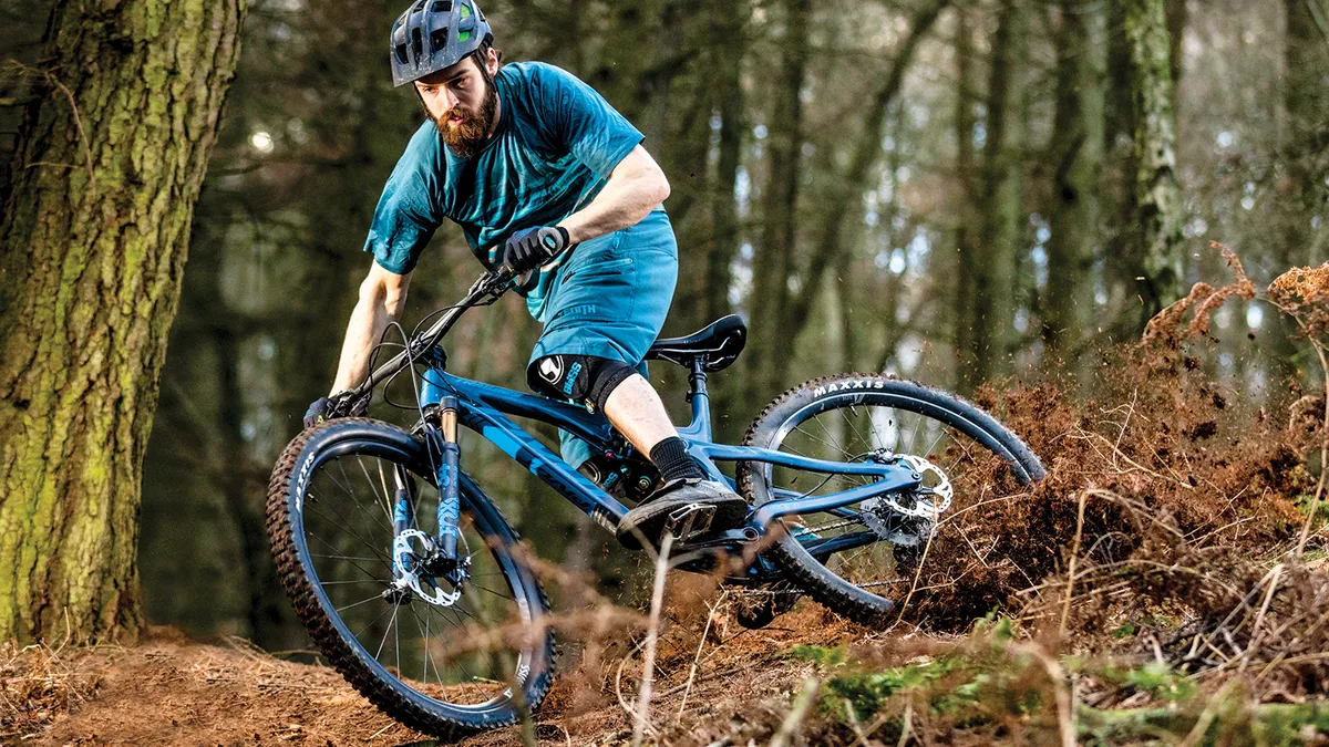 Male cyclist rides mountain bike in woodland