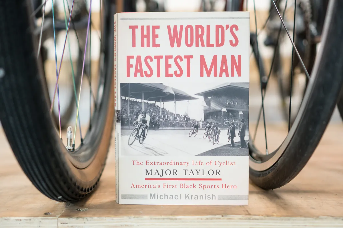 Cycling book, The World's Fastest Man by Major Taylor, between two bike wheels