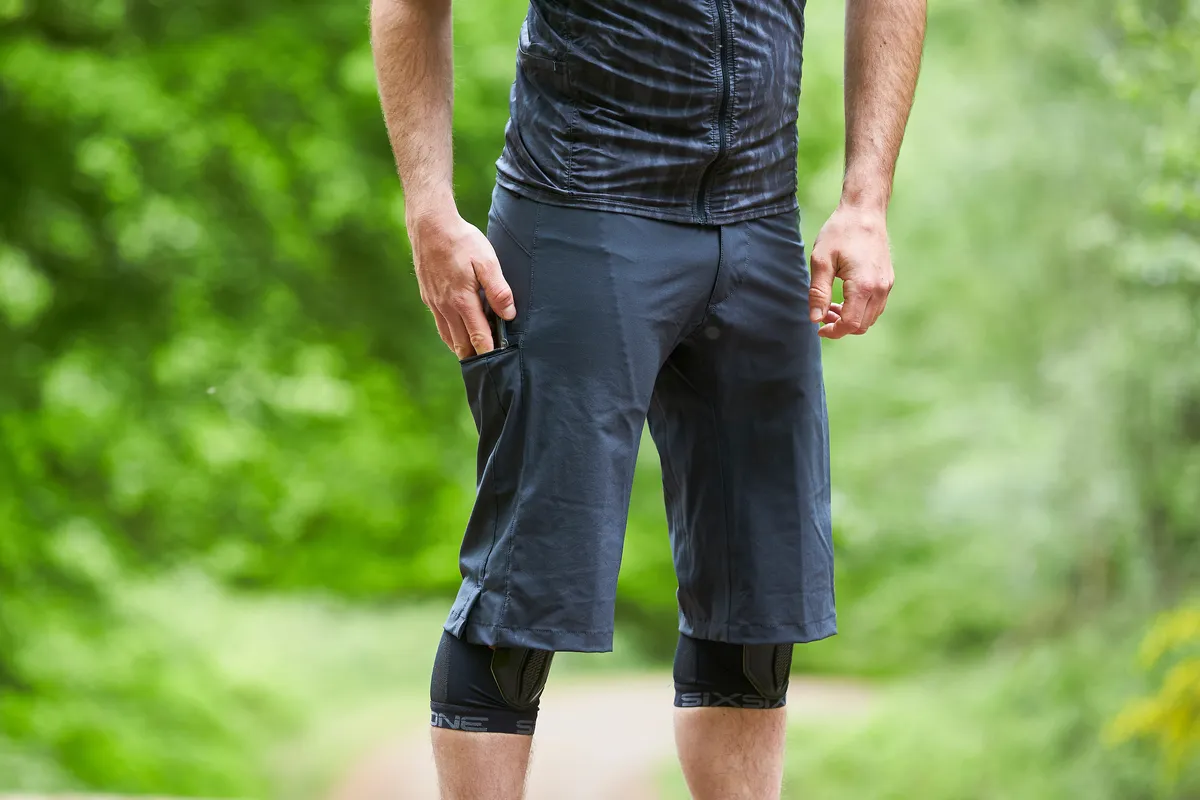 Man wears Mission Workshop The Traverse shorts with one hand in right hand pocket