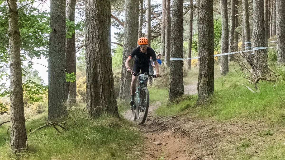 male cyclist riding mountain bike through woodland
