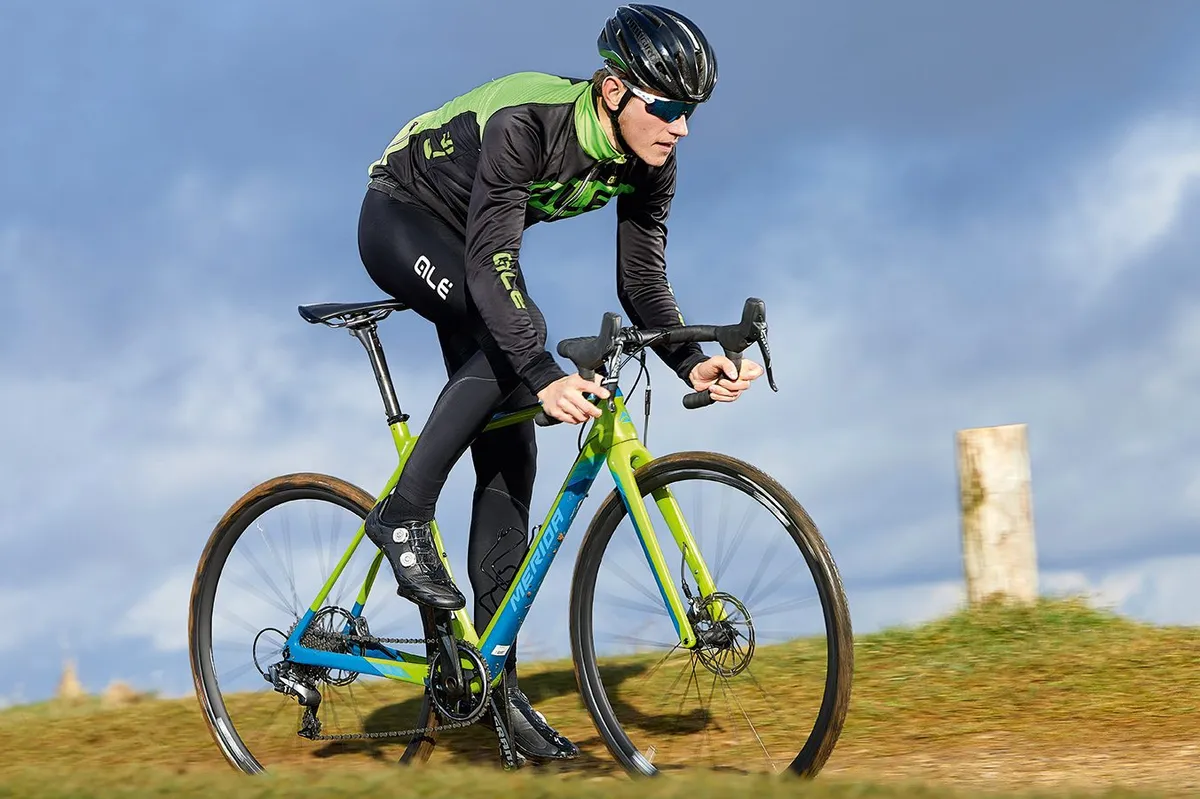Male cyclist riding green and blue road bike in countryside