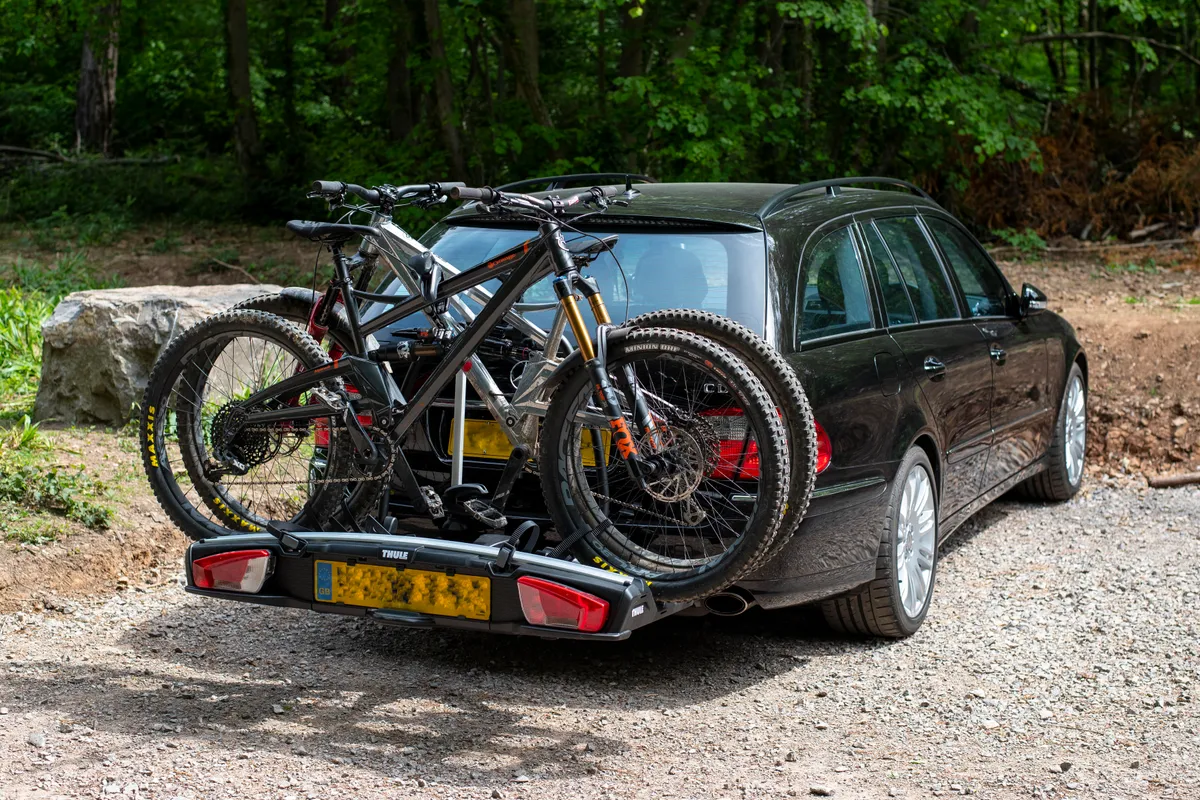 Thule VeloSpace XT3 tow bar mounted bike rack attached to a black car with two bicycles loaded