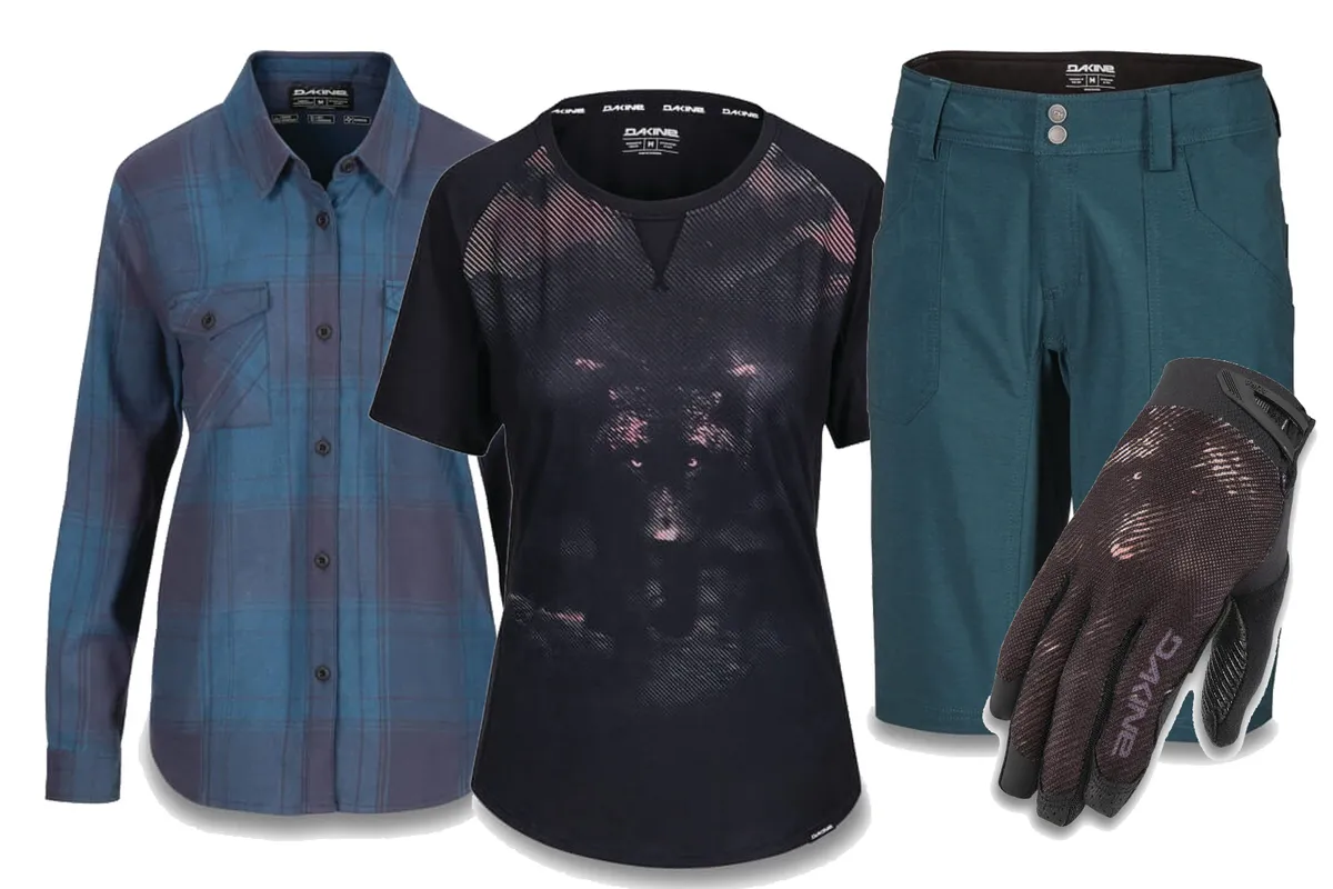 A selection of women's mountain bike clothing from Dakine with a blue shirt, black T-shirt, dark green shorts and black gloves