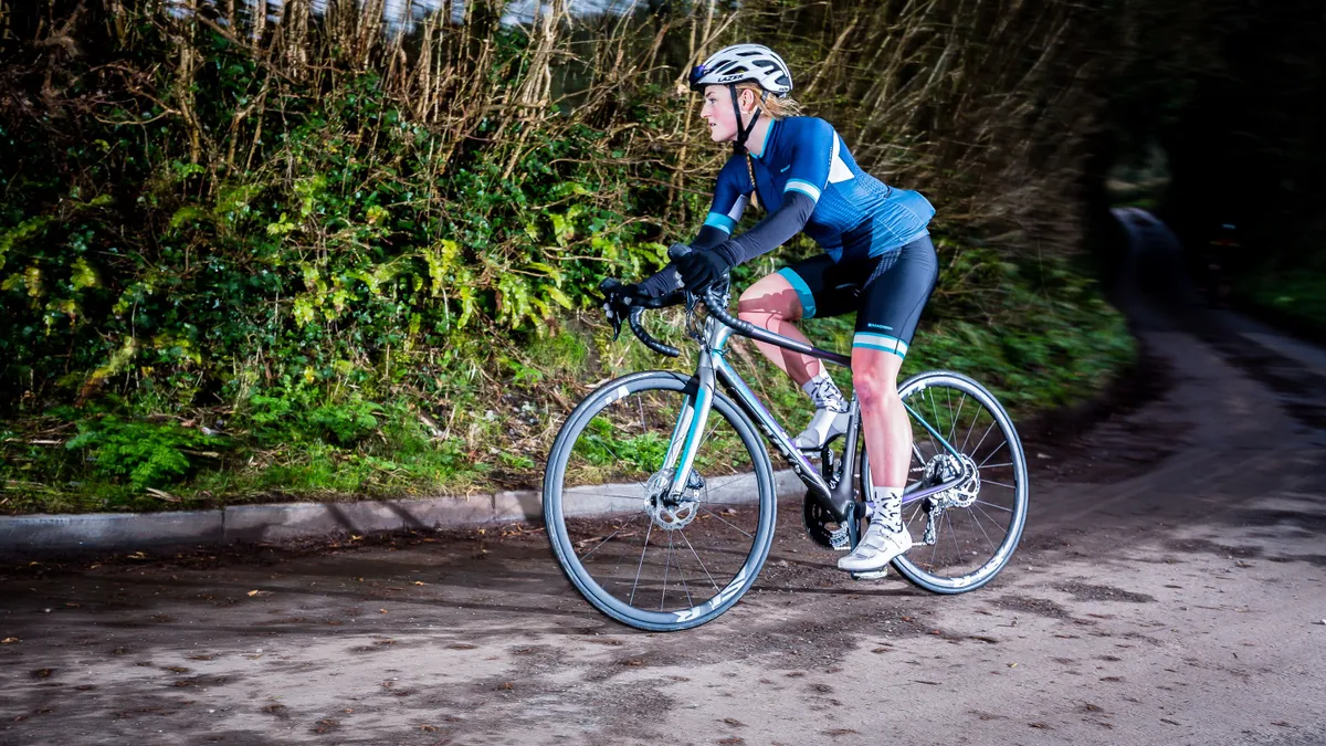 Woman riding road bike in blue kit on a country lane