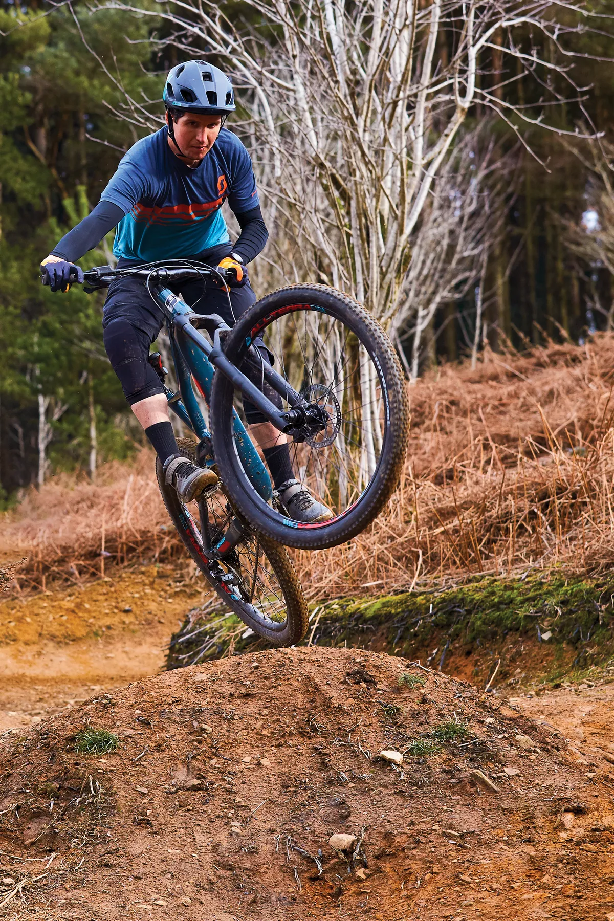 Male cyclist riding blue full suspension mountain bike in woods