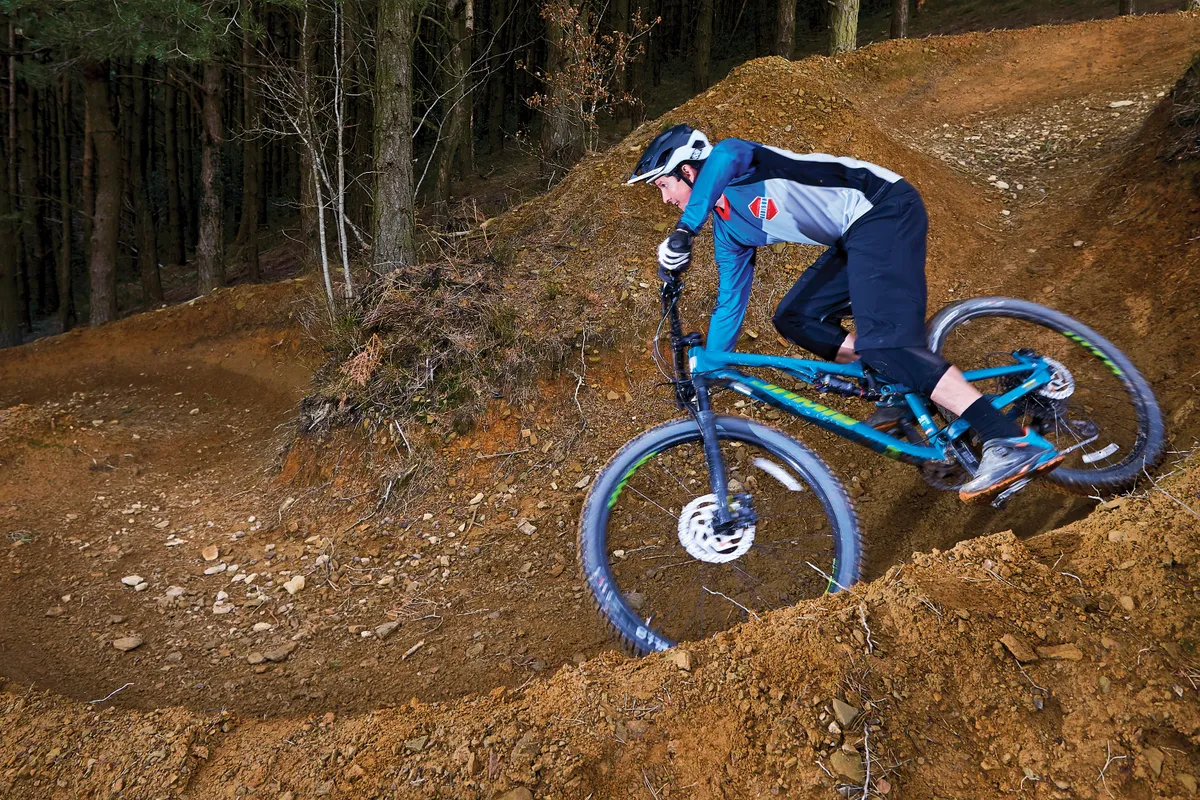 Male cyclist riding blue full suspension mountain bike down hill