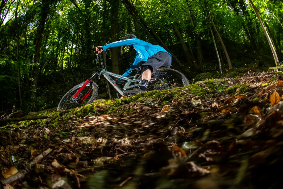 BikeRadar Technical Editor Alex Evans rides his long-term Orange Stage 6 RS enduro mountain bike around a bermed corner in the forest