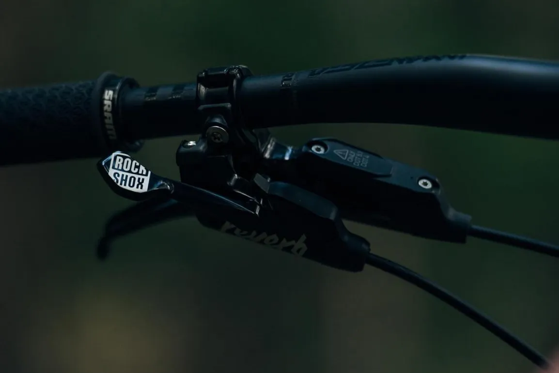 Detail photograph of the controls of the RockShox Reverb Stealth dropper post mounted on a bicycle handlebar