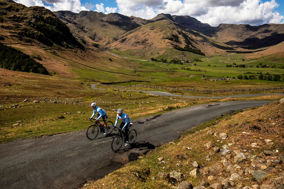 Two cyclists from Team Alpecin riding road bikes in mountains