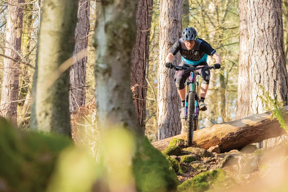 Cyclist riding full-suspension mountain bike through woods
