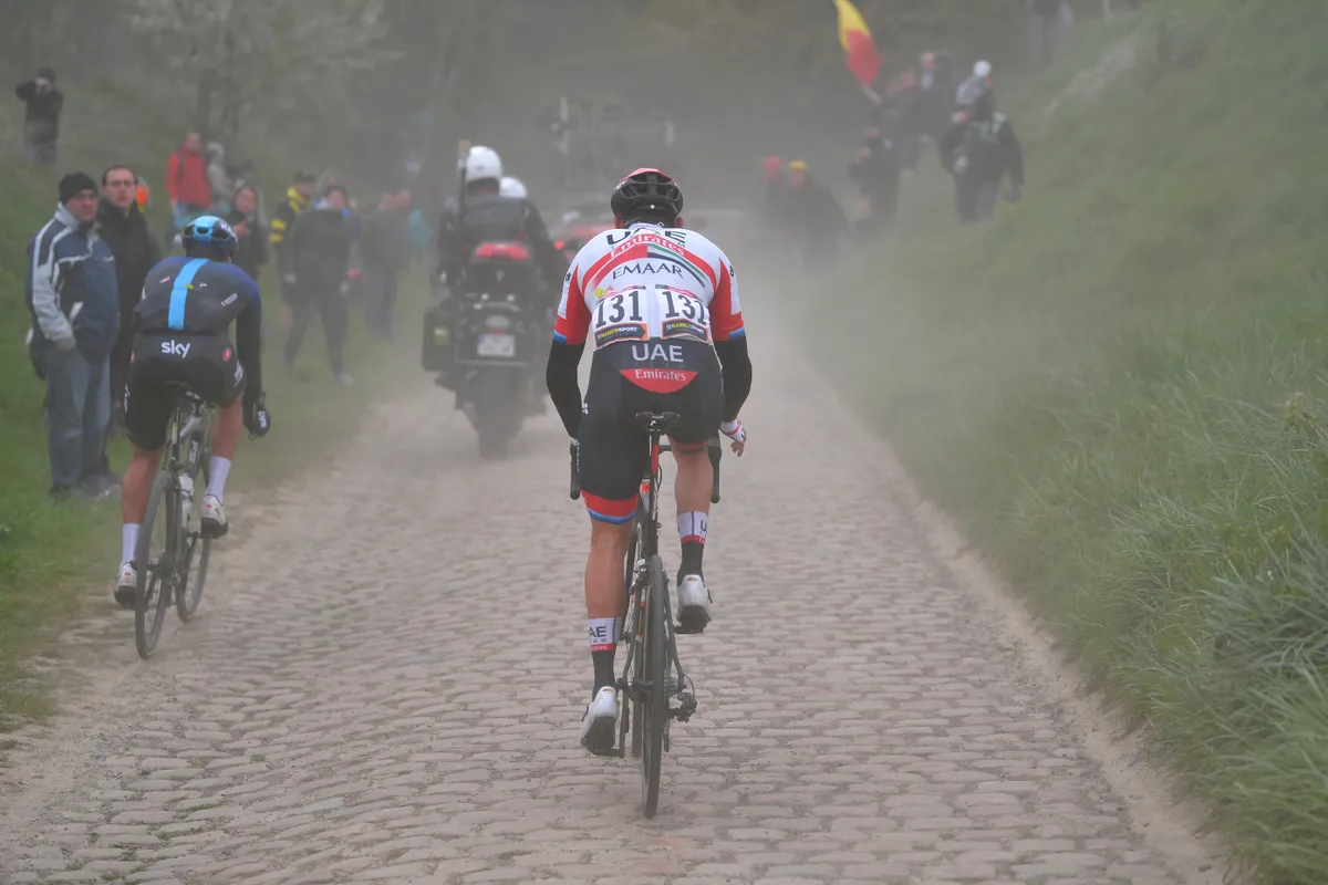 Pro cyclist riding in the dust behind the peloton at Paris–Roubaix