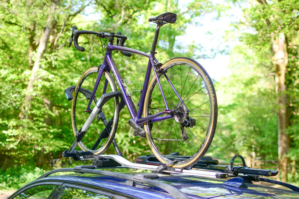 Purple bike on roof-mounted bike rack, on car