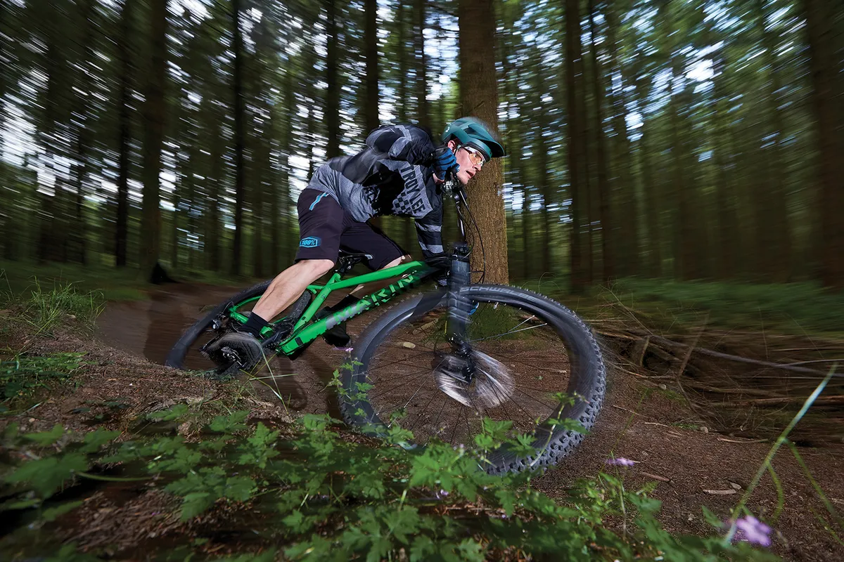 male cyclist riding green hardtail mountain bike in woods