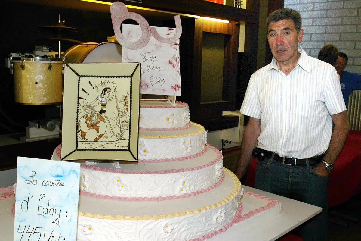 Eddy Merckx standing next to giant layered birthday cake