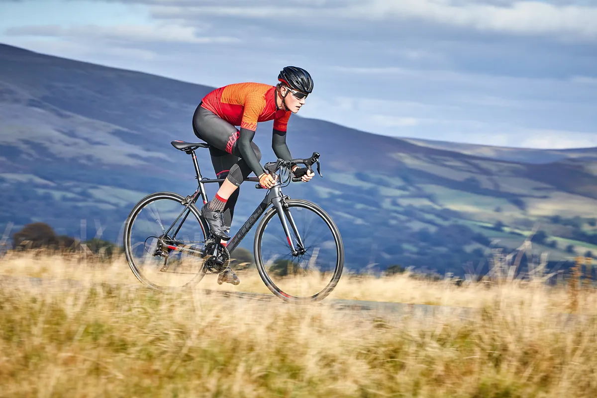Male cyclist in red top riding grey Carrera road bike