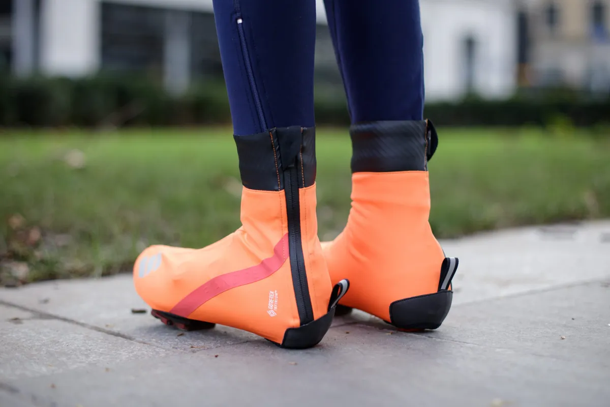 Orange overshoes from behind, showing zips and pull-tabs on heels
