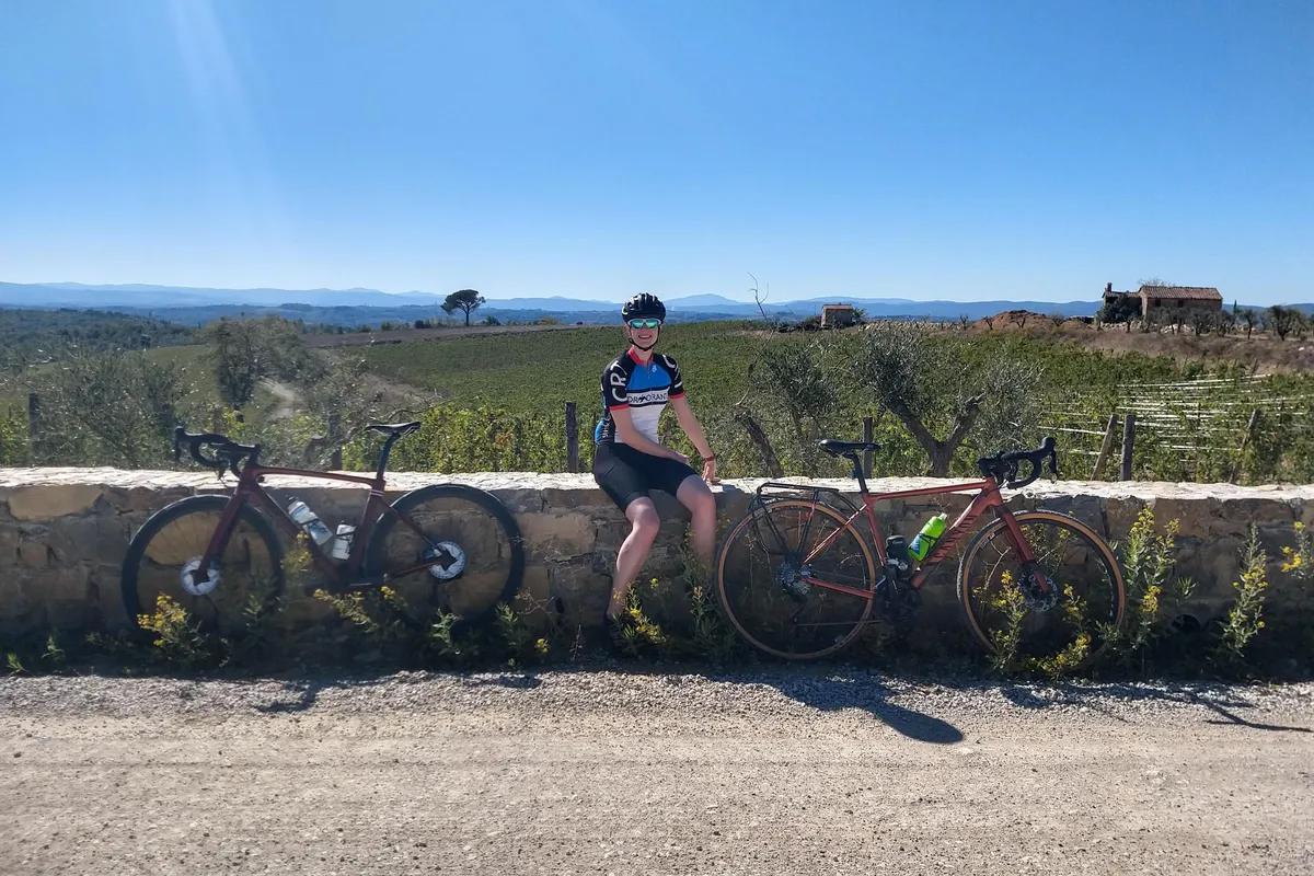 Cyclist sitting on wall in Tuscany with bikes either side