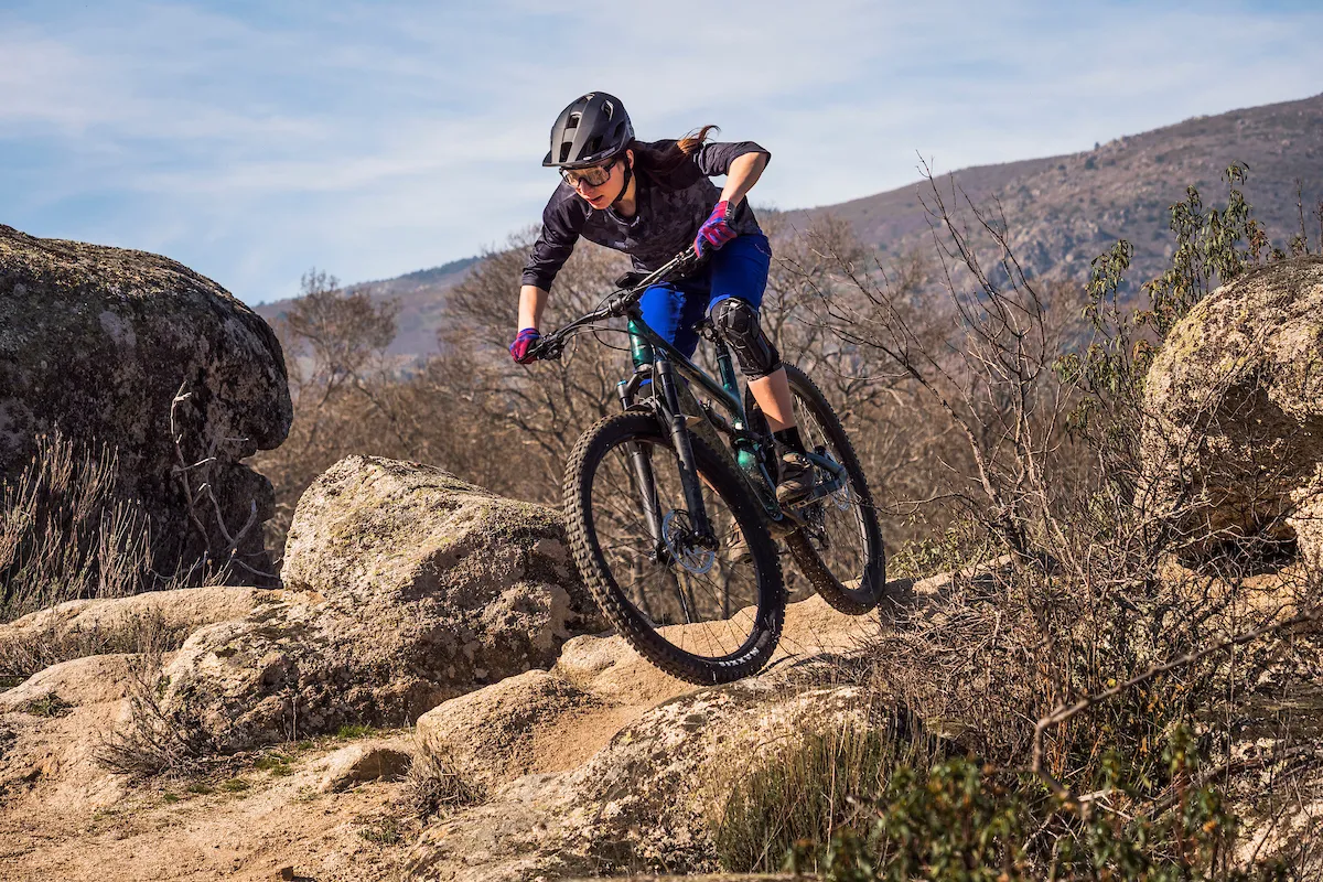 Cyclist riding a Cannondale Habit Carbon 3 full-suspension mountain bike over rocky terrain