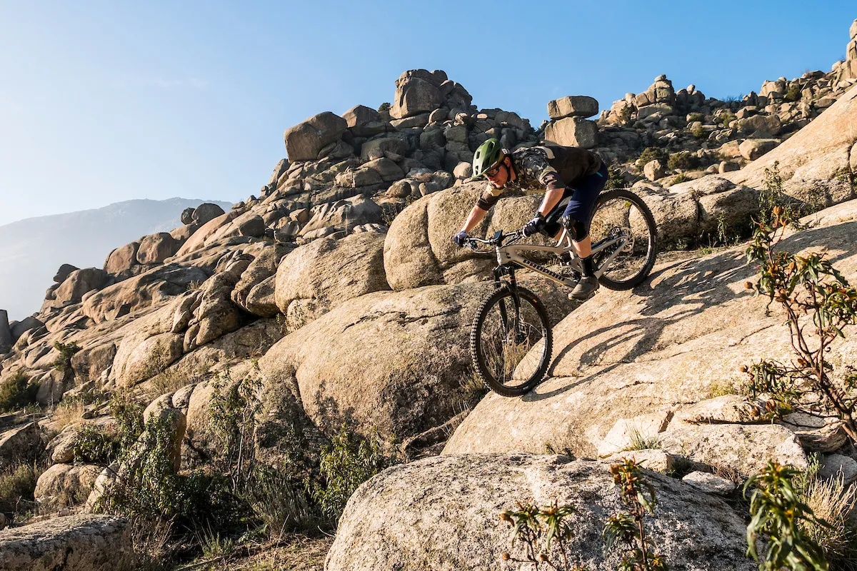 Cyclist riding full suspension mountain bike over rocks
