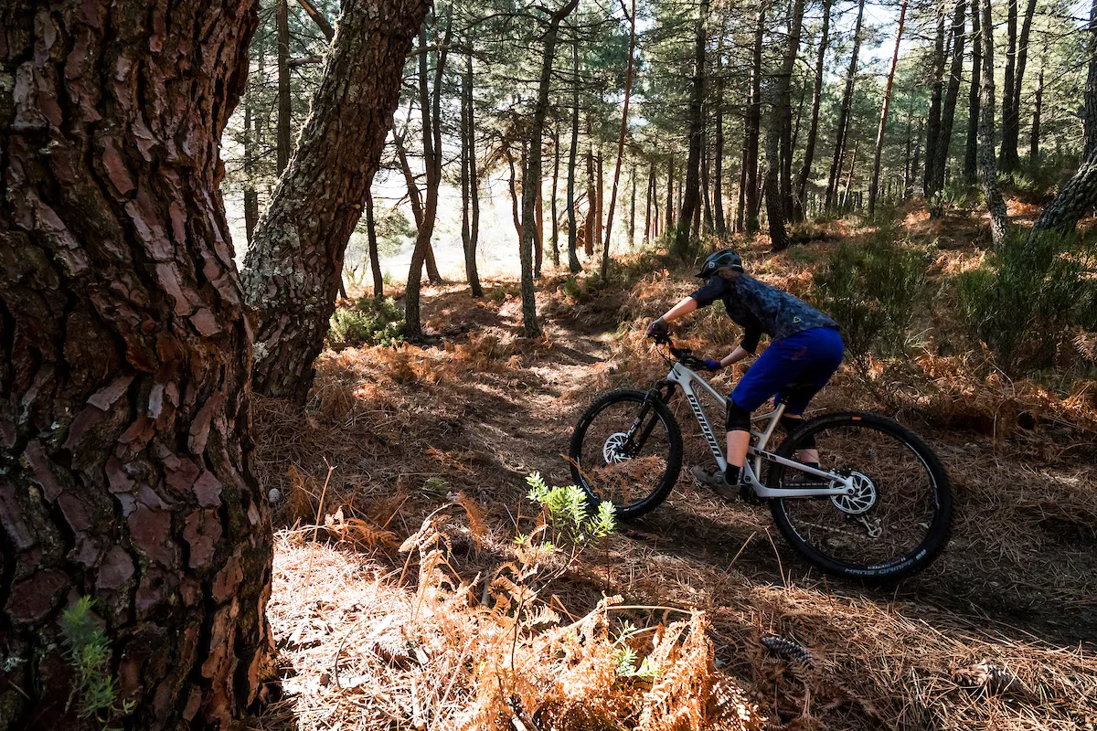 Cyclist riding full suspension mountain bike through woods