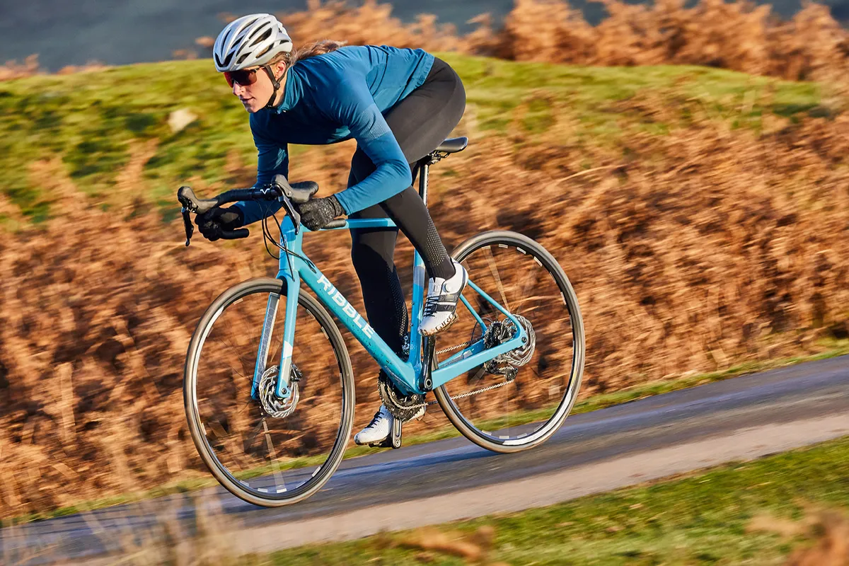 Cyclist in blue top riding a teal coloured road bike from Ribble