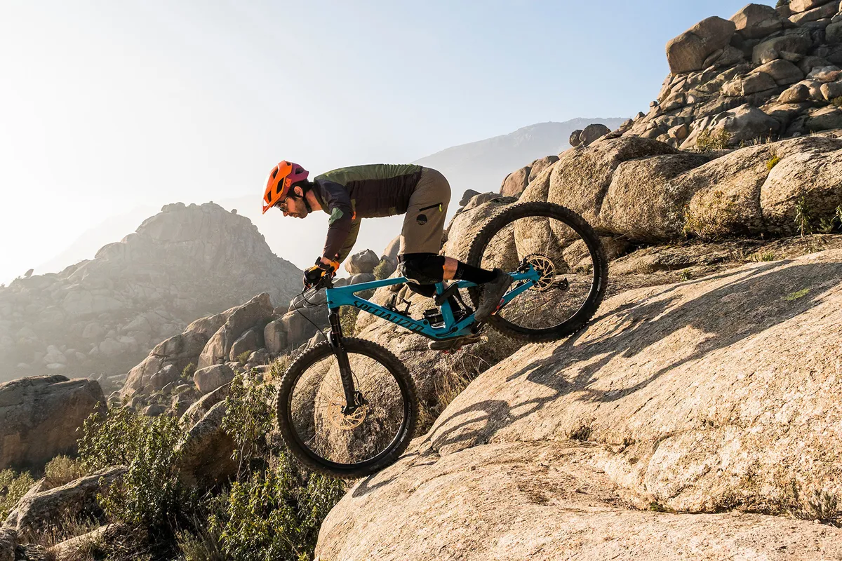 Cyclist riding Specialized Enduro Comp full-suspension mountain bike over rocks