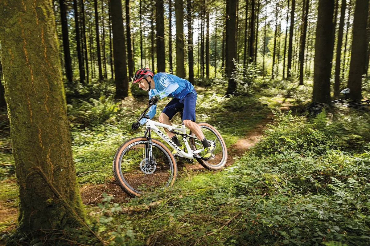 Cyclist in blue top riding the Specialized Epic Pro full-suspension mountain bike