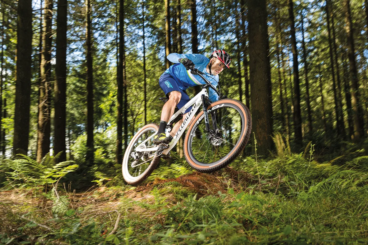 Cyclist in blue top riding the Specialized Epic Pro full-suspension mountain bike