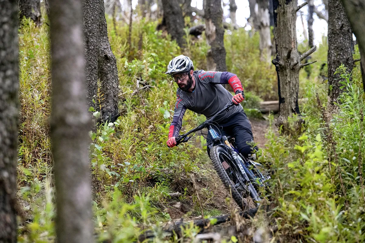 Male cyclist riding a full suspension mountain bike through woodland