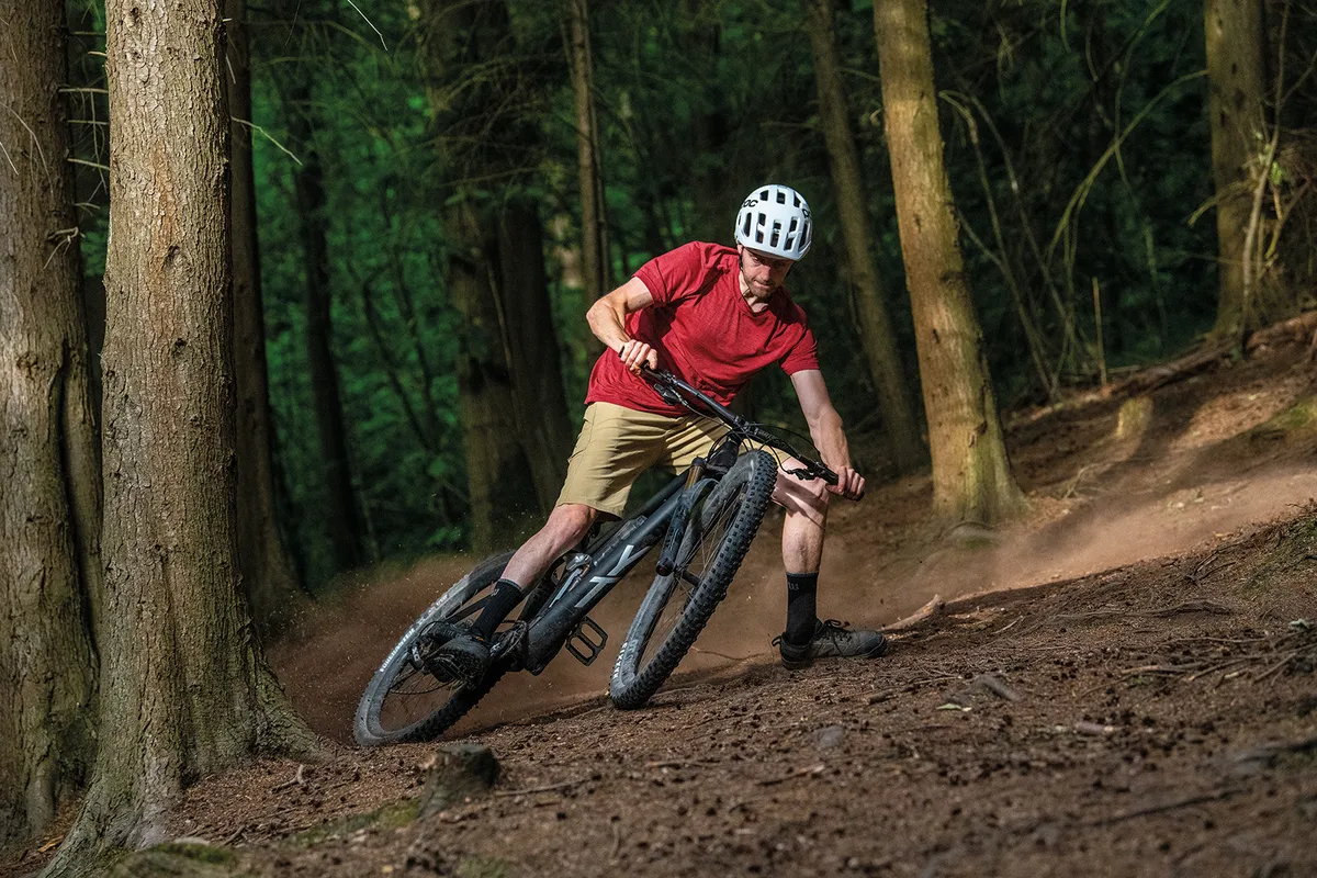 Cyclist in red top riding the YT Izzo Pro Race full-suspension mountain bike