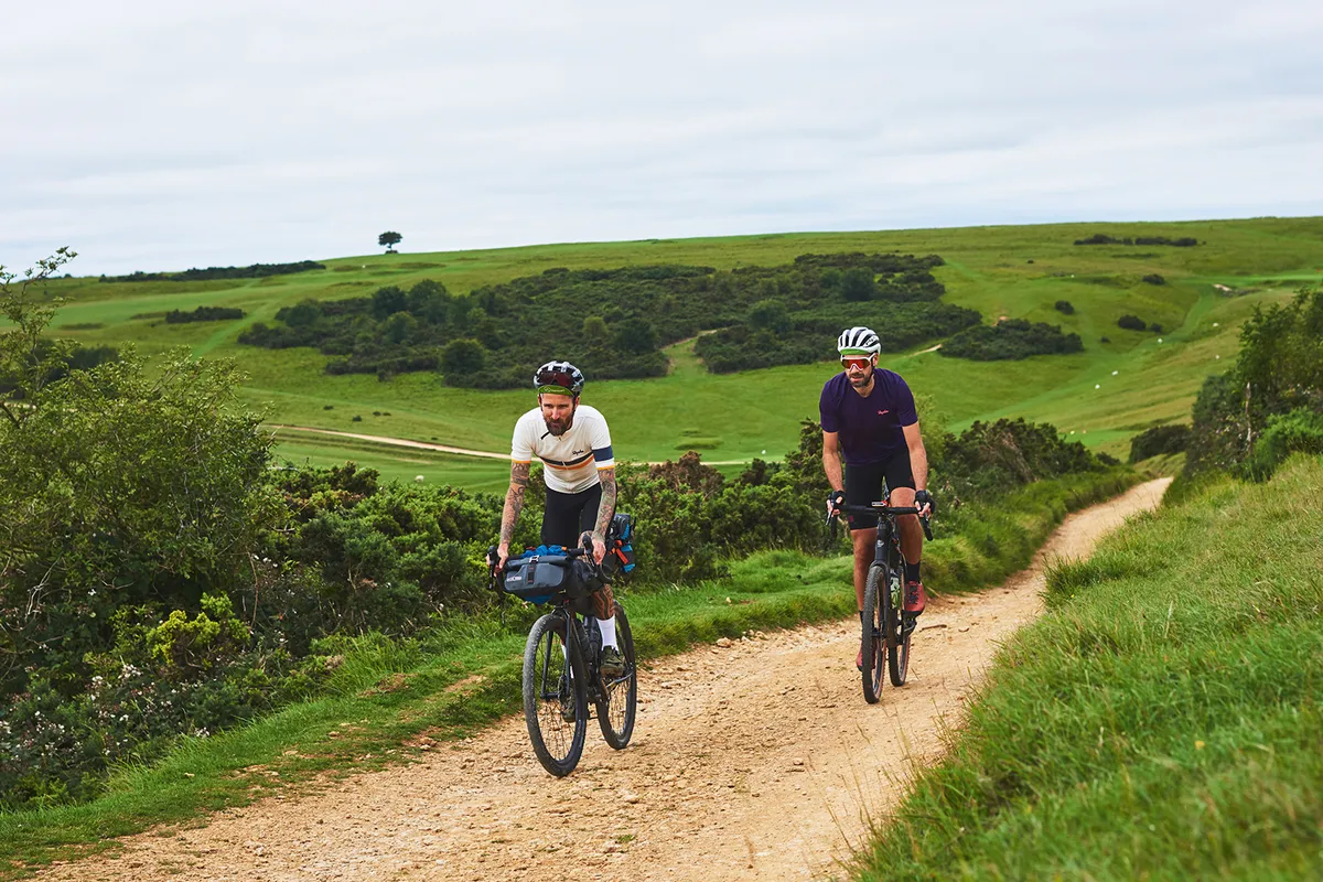 Two male cyclists riding through the countryside on touring bikes