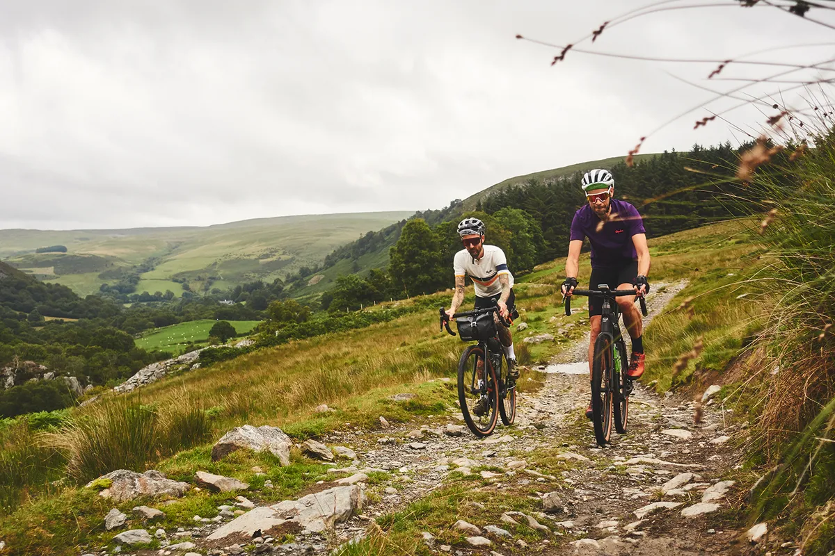 Two male cyclists riding gravel bikes through the countryside in Wales while on one of the Komoot routes