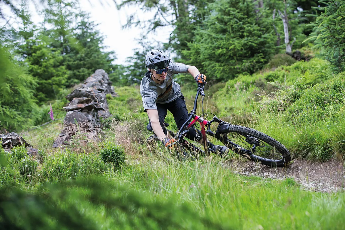 Cyclist in a grey top riding a Ragley Piglet hardtail mountain bike over rough ground