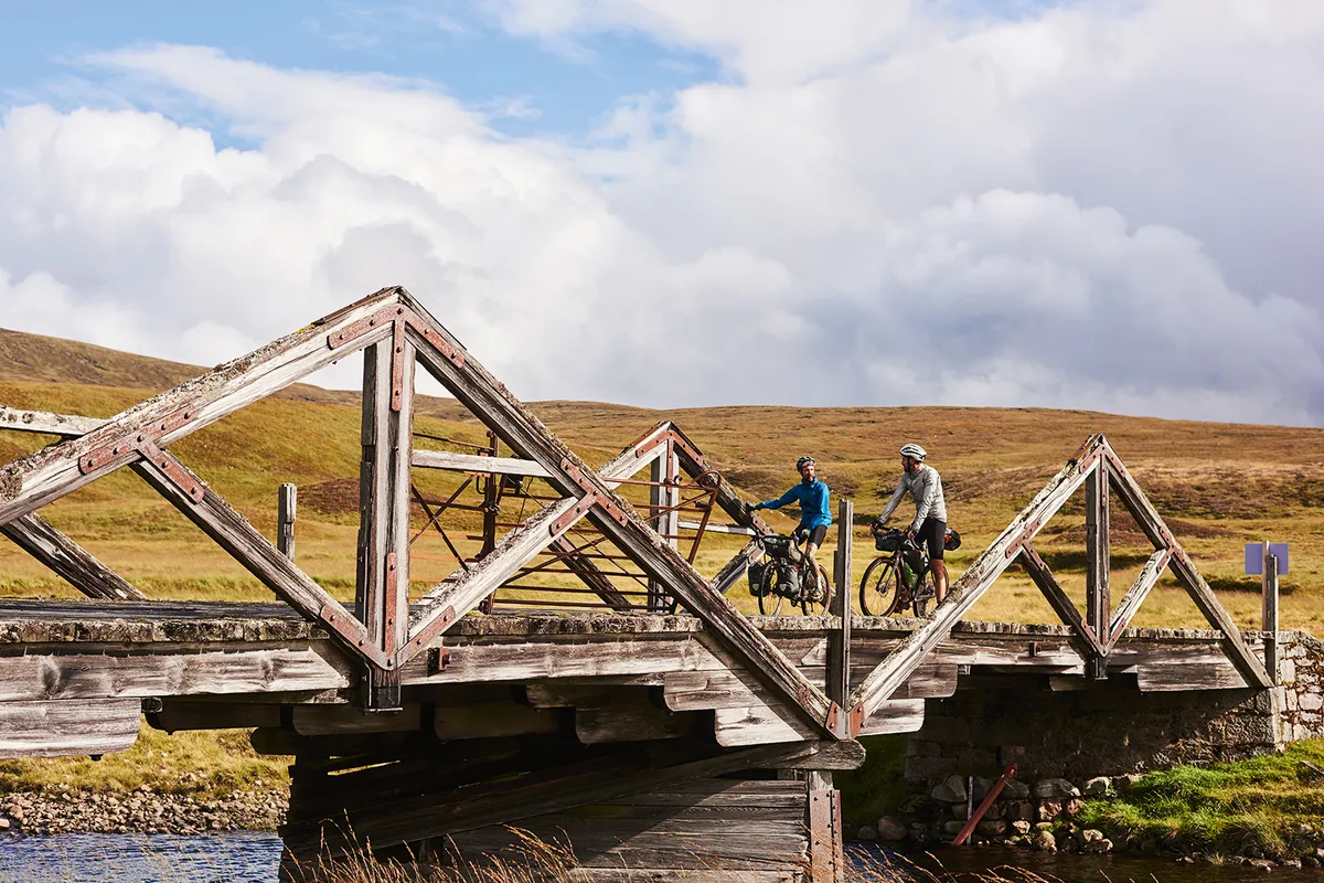Cyclists crossing a bridge during their bikepacking through the Scottish Highlands