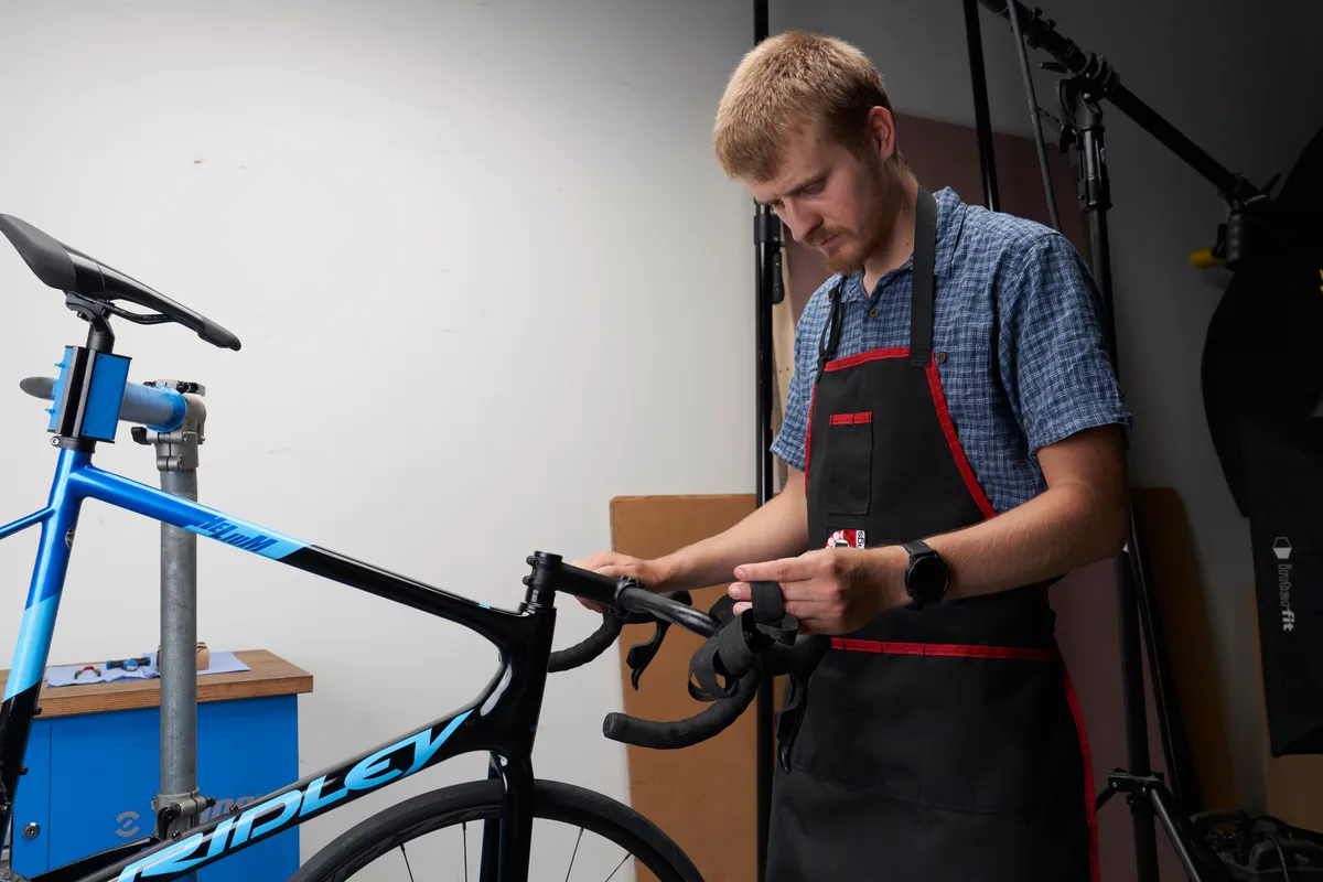 Mechanic removing bar tape from a Ridley Helium Disc