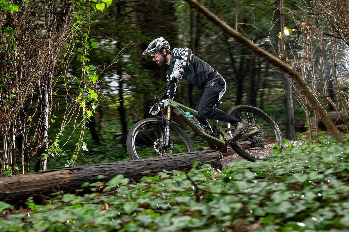 Cyclist riding the new Nukeproof Giga full suspension mountain bike through woodland
