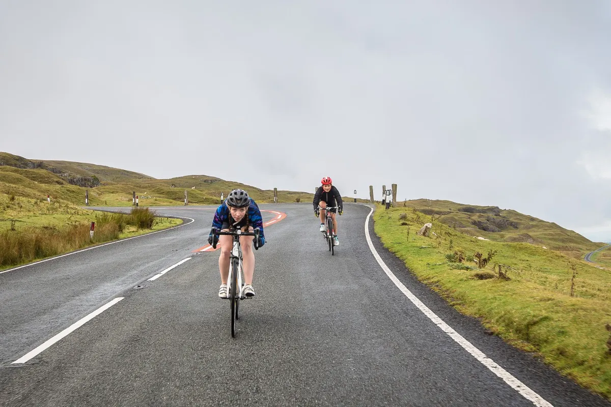 Two female cyclists descending a mountain road in the Brecon Beacons
