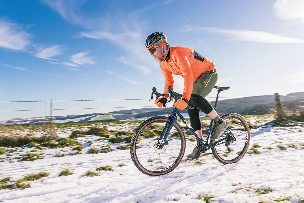 Cyclist in bright orange top riding a Ragely Trig 2021 gravel bike on snow