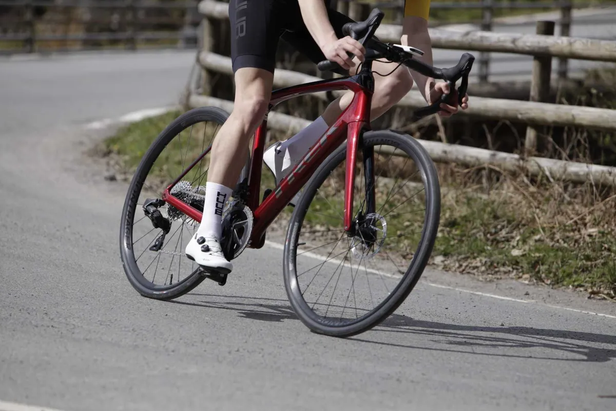 Close-up of fully-extended cyclist's leg while riding around corner.