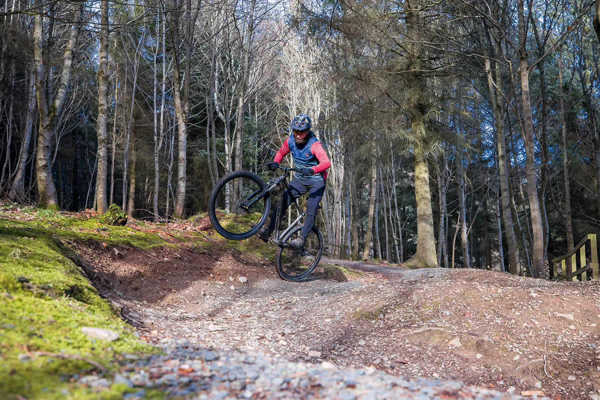 Cyclist in blue and red top riding the Cannondale Trail SE4 hardtail mountain bike through woodland