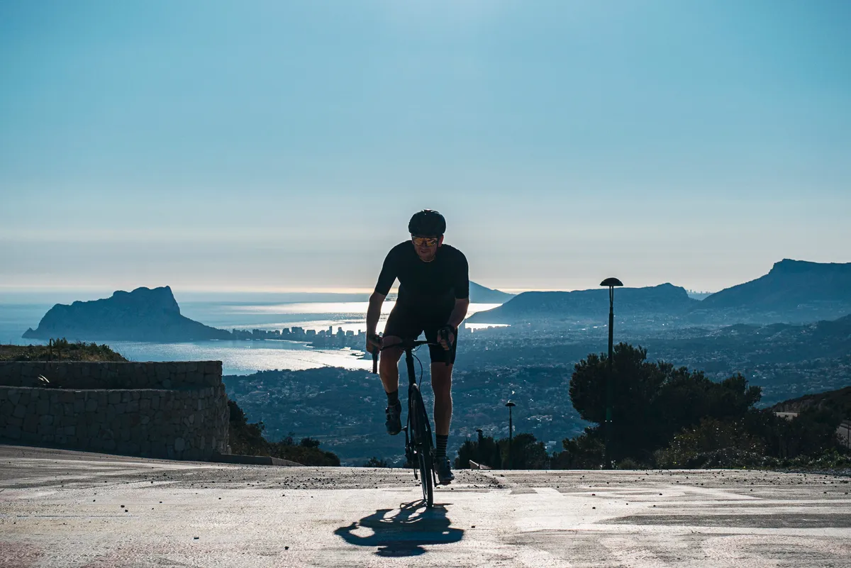 Cyclist climbing with view of Calpe behind