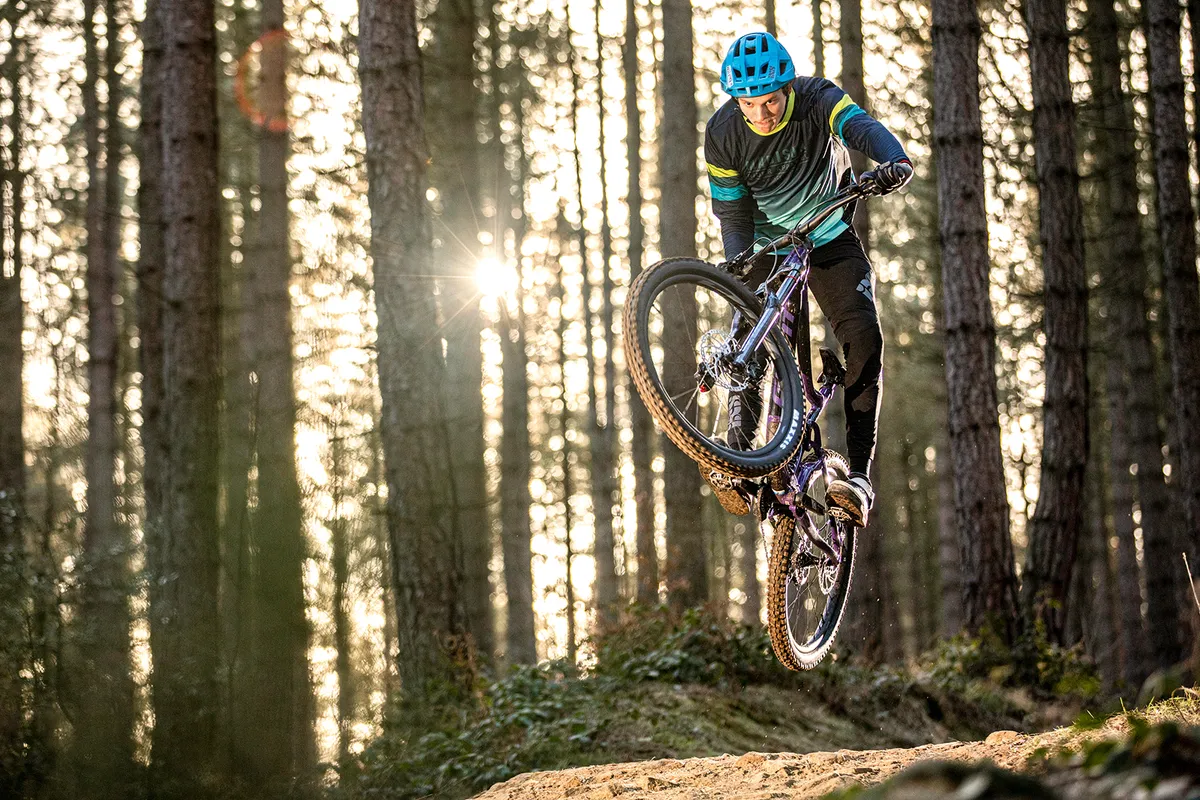 Cyclist riding the Giant Reign SX full suspension mountain bike through woodland