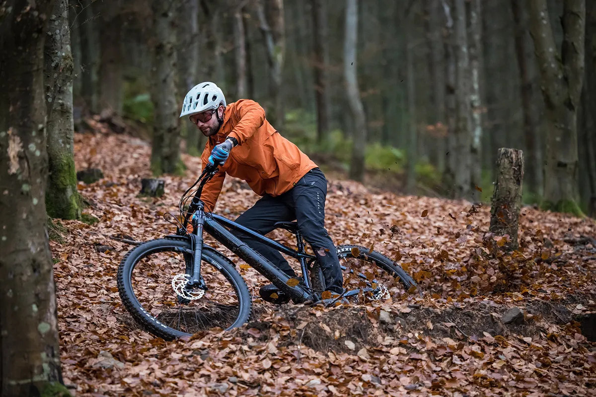Cyclist riding the hardtail Kinesis Rise Pro eMTB through woodland