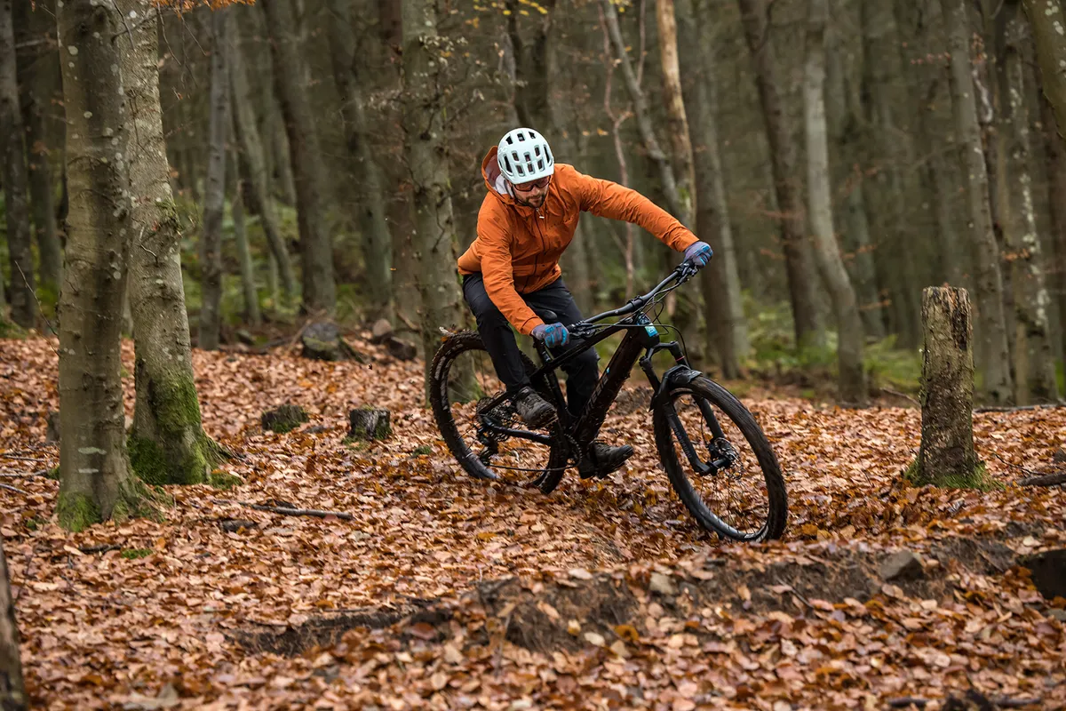 Male cyclist riding the hardtail Kinesis Rise Pro eMTB through woodland