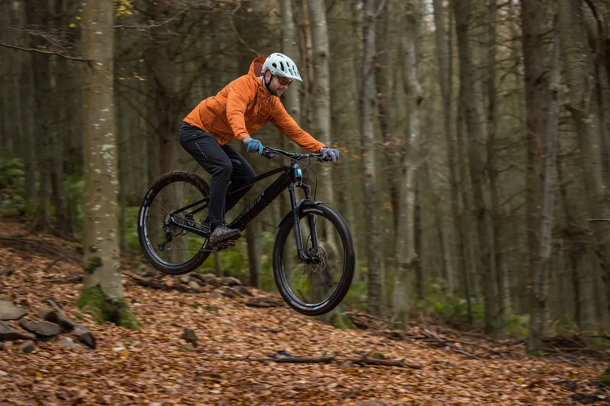 Male cyclist riding the hardtail Kinesis Rise Pro eMTB through woodland