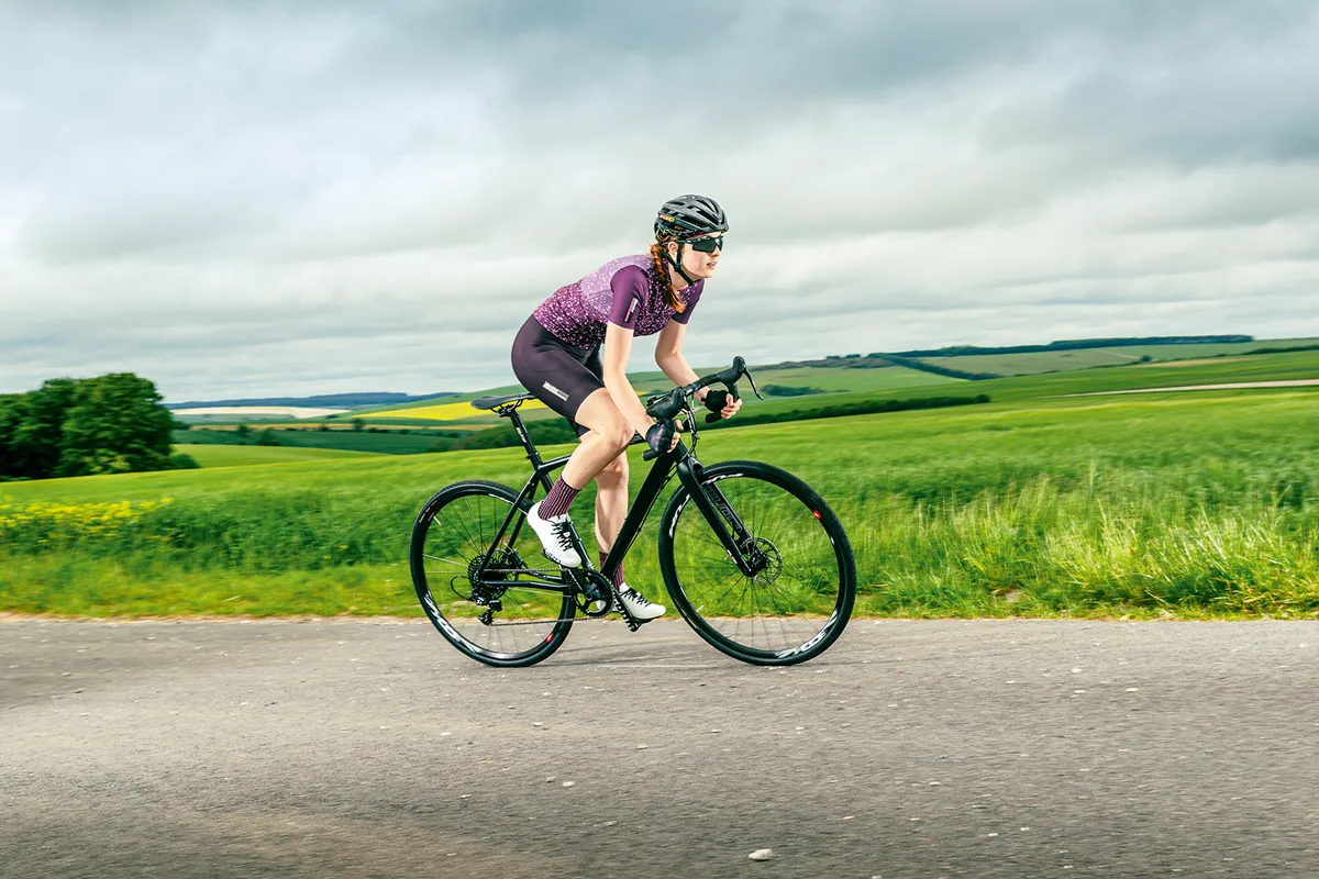 Female cyclist riding a Planet X London Road through the country side